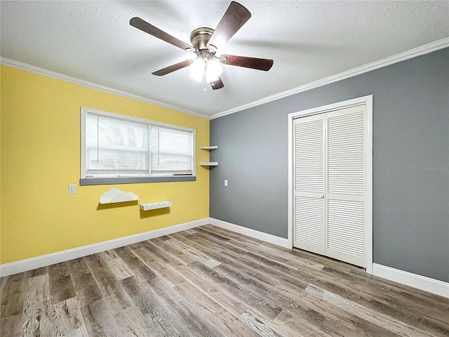 unfurnished bedroom featuring hardwood / wood-style flooring, ceiling fan, ornamental molding, and a closet