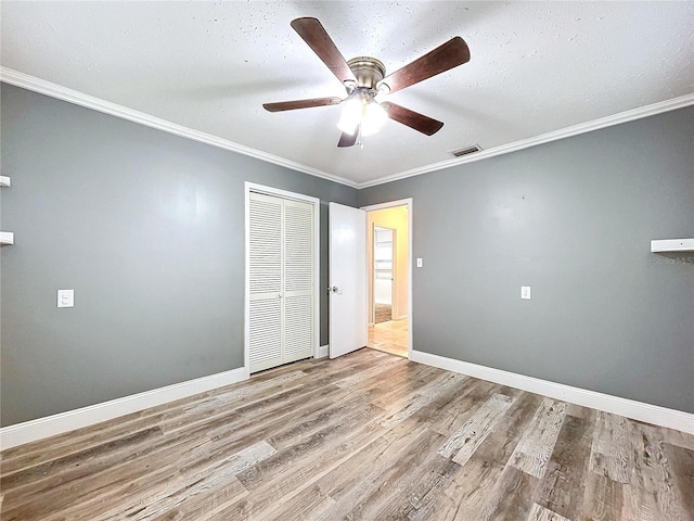 unfurnished bedroom with hardwood / wood-style flooring, ceiling fan, ornamental molding, and a closet