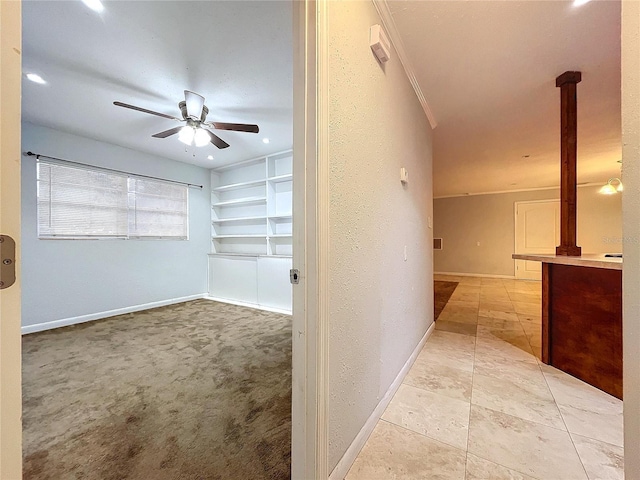 corridor with crown molding, light carpet, and built in shelves