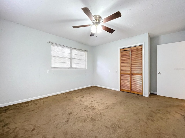 unfurnished bedroom with ceiling fan, dark carpet, and a closet