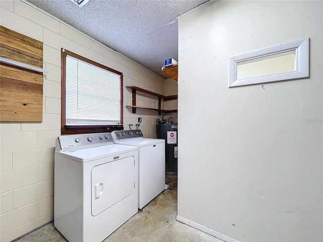 clothes washing area with washing machine and clothes dryer, water heater, and a textured ceiling