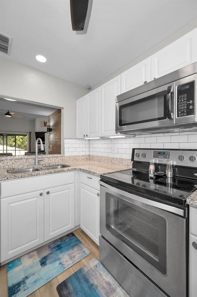 kitchen featuring white cabinetry, stainless steel appliances, light hardwood / wood-style flooring, sink, and decorative backsplash