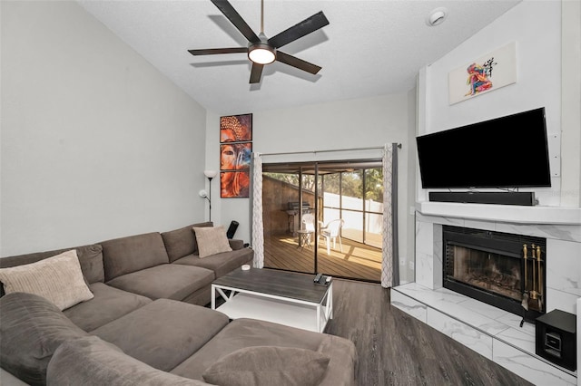 living room featuring a textured ceiling, a tiled fireplace, vaulted ceiling, and ceiling fan