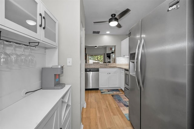 kitchen featuring appliances with stainless steel finishes, sink, light hardwood / wood-style flooring, ceiling fan, and white cabinets