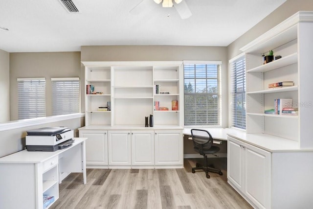 office area with built in desk, ceiling fan, and light hardwood / wood-style flooring