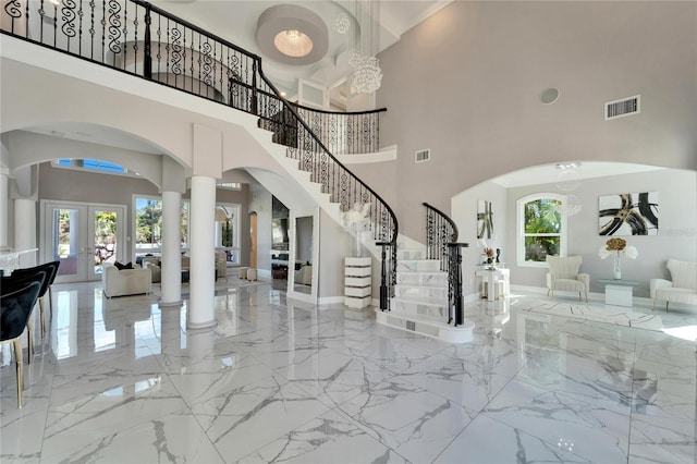 foyer featuring french doors, a chandelier, and ornate columns