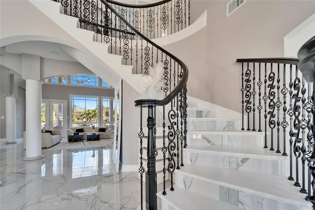 staircase featuring ornate columns, a towering ceiling, and french doors