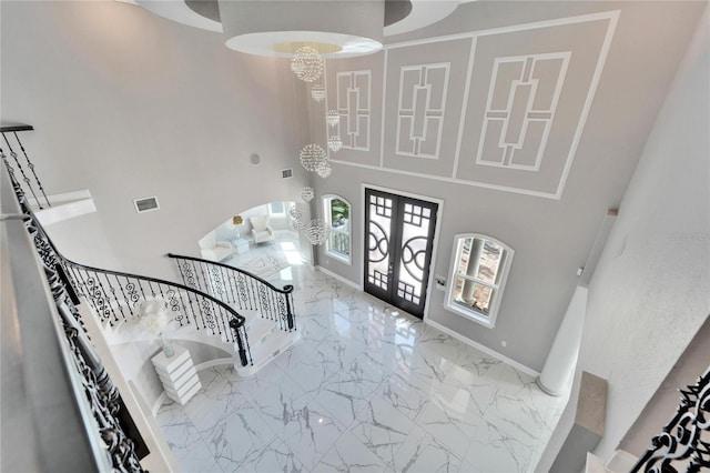 foyer featuring an inviting chandelier, french doors, and a high ceiling