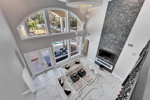 living room featuring french doors, a towering ceiling, and a chandelier