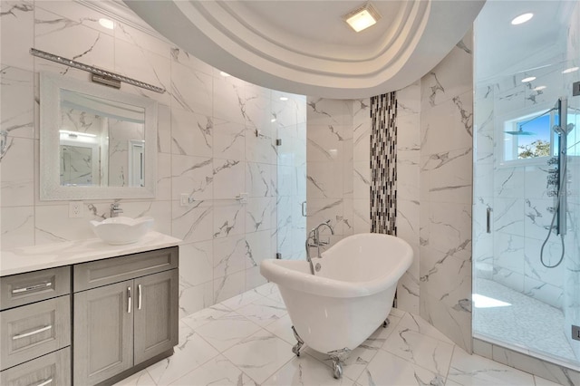 bathroom with tile walls, vanity, independent shower and bath, and a raised ceiling