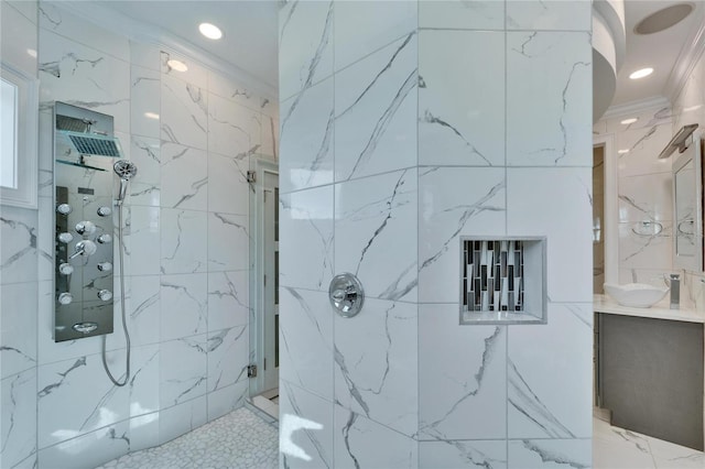 bathroom featuring a tile shower, vanity, and ornamental molding