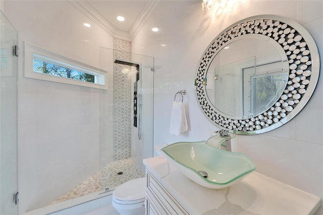 bathroom with crown molding, tiled shower, vanity, and toilet