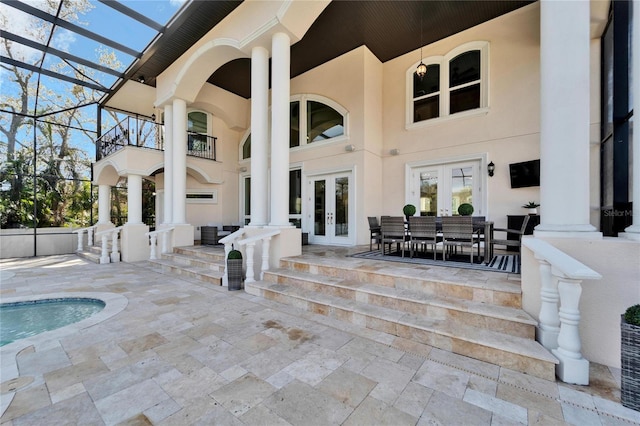 exterior space featuring a balcony, glass enclosure, and french doors