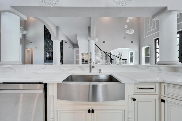 9401 93rd St, Seminole, FL 33777 - kitchen featuring stainless steel dishwasher, a sink, arched walkways, light stone counters, and white cabinets