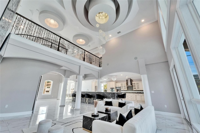 9401 93rd St, Seminole, FL 33777 - living area with light marble finish flooring, a high ceiling, baseboards, decorative columns, and a chandelier