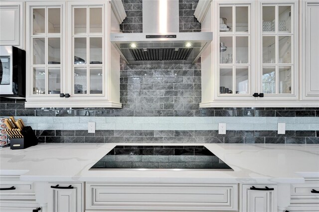 9401 93rd St, Seminole, FL 33777 - kitchen featuring wall chimney exhaust hood, stainless steel microwave, black electric cooktop, and glass insert cabinets
