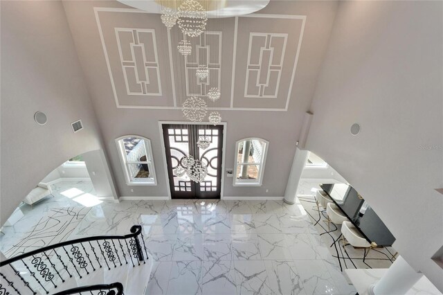 9401 93rd St, Seminole, FL 33777 - entrance foyer featuring a chandelier, marble look tile flooring, arched walkways, a towering ceiling, and french doors