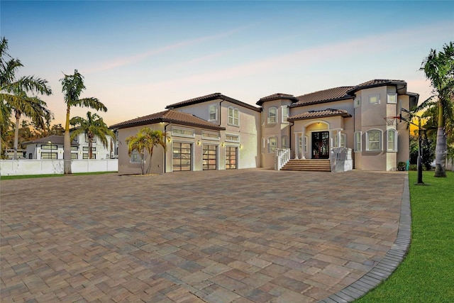 9401 93rd St, Seminole, FL 33777 - mediterranean / spanish-style home with decorative driveway, stucco siding, fence, a tile roof, and a garage