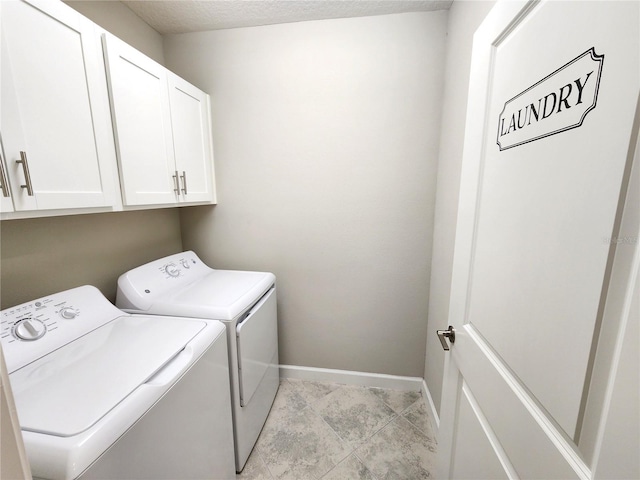 laundry area featuring washer and clothes dryer, cabinets, and a textured ceiling