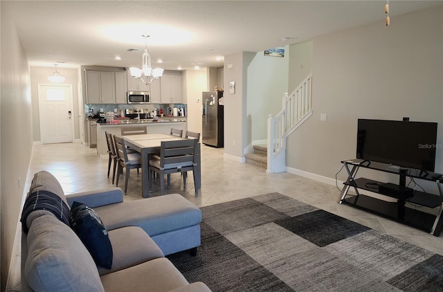 living room featuring stairway, baseboards, a chandelier, light tile patterned flooring, and visible vents