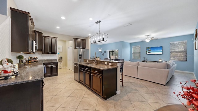 kitchen featuring pendant lighting, sink, stainless steel appliances, an island with sink, and light tile patterned flooring