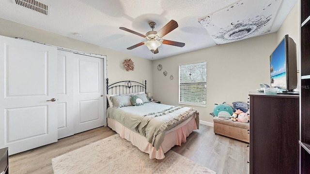 bedroom featuring light wood-type flooring, ceiling fan, and a closet