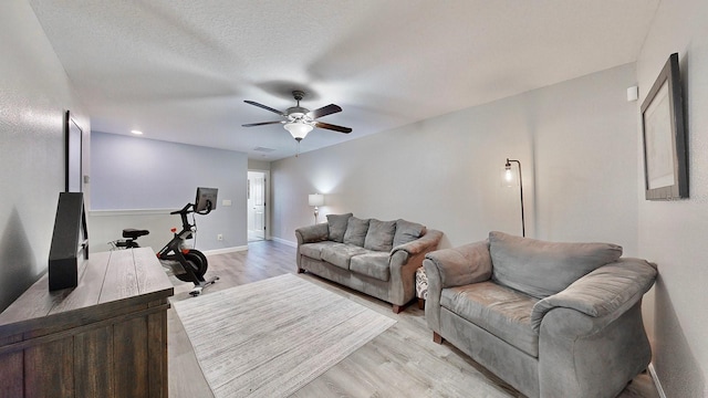 living room with ceiling fan, light hardwood / wood-style floors, and a textured ceiling