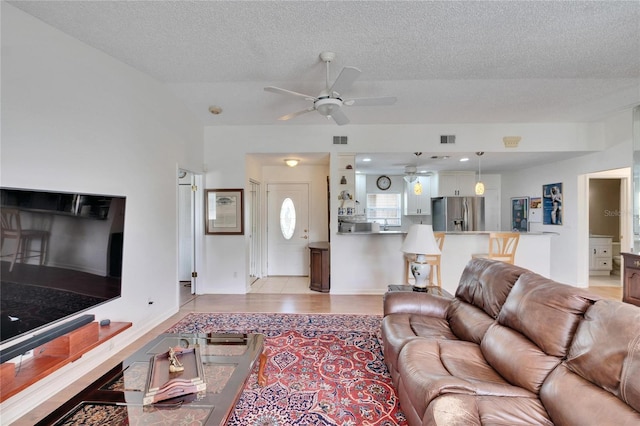 living room with a textured ceiling and ceiling fan