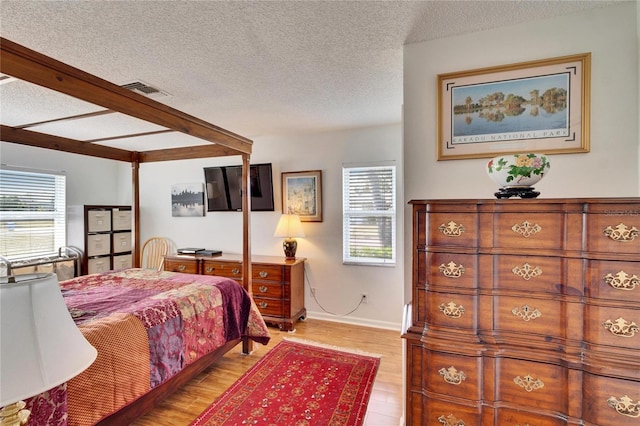 bedroom featuring multiple windows, light hardwood / wood-style floors, and a textured ceiling