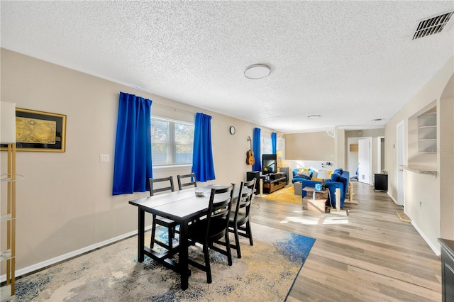 dining area featuring light hardwood / wood-style floors and a textured ceiling