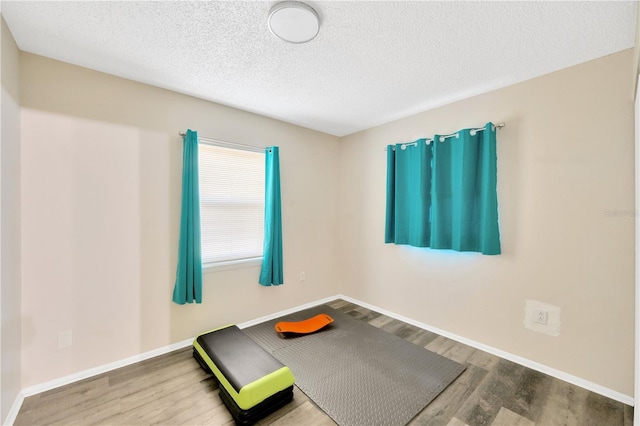 exercise area with hardwood / wood-style flooring and a textured ceiling