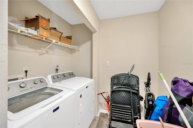 clothes washing area with a textured ceiling, washer and clothes dryer, and light hardwood / wood-style flooring