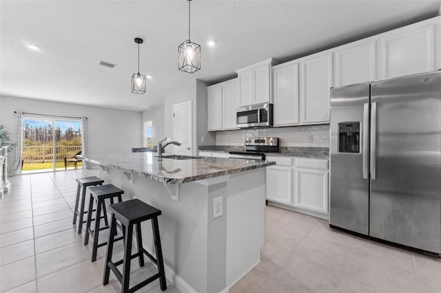 kitchen featuring appliances with stainless steel finishes, pendant lighting, white cabinetry, sink, and a kitchen island with sink