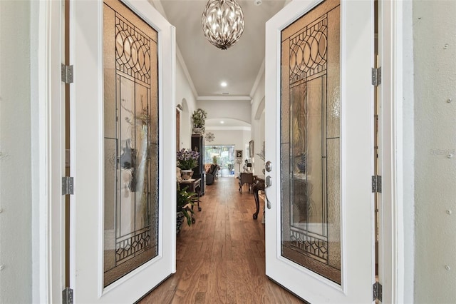 entrance foyer with a notable chandelier, crown molding, and wood-type flooring