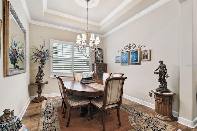 dining room featuring hardwood / wood-style flooring, crown molding, a raised ceiling, and an inviting chandelier