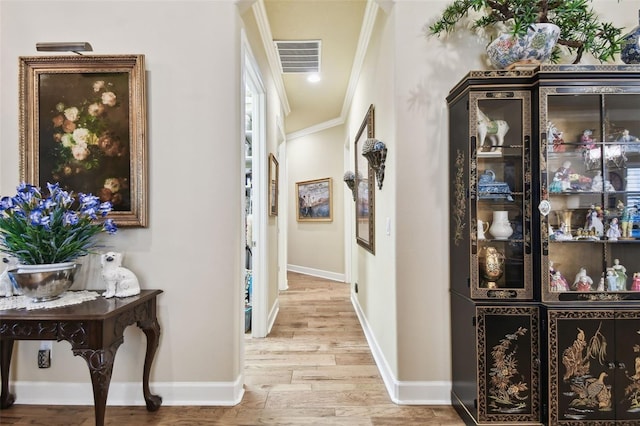 corridor featuring ornamental molding and light hardwood / wood-style floors