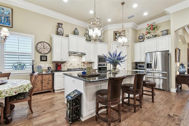 kitchen with stainless steel appliances, decorative light fixtures, a kitchen island with sink, and white cabinets