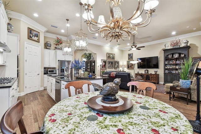 dining area with dark hardwood / wood-style flooring, sink, ceiling fan with notable chandelier, and ornamental molding