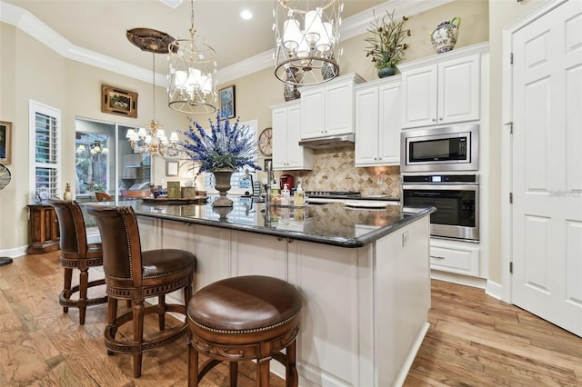 kitchen with white cabinetry, crown molding, a chandelier, an island with sink, and stainless steel appliances