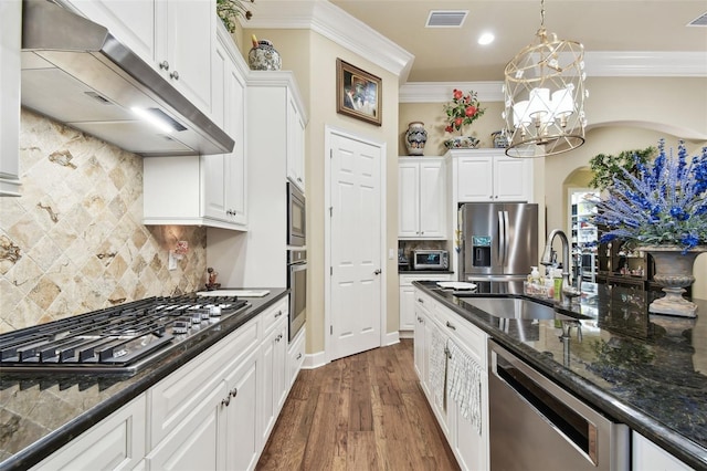 kitchen with sink, crown molding, appliances with stainless steel finishes, white cabinetry, and range hood