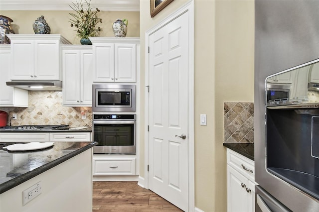 kitchen featuring dark wood-type flooring, white cabinetry, crown molding, tasteful backsplash, and appliances with stainless steel finishes