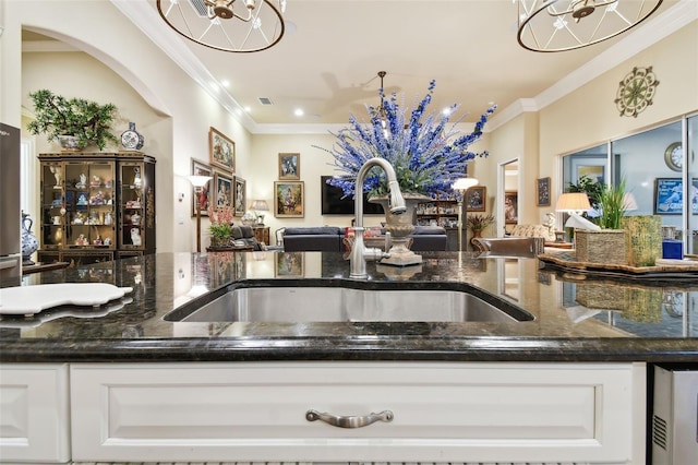 kitchen with white cabinetry, sink, crown molding, and dark stone countertops