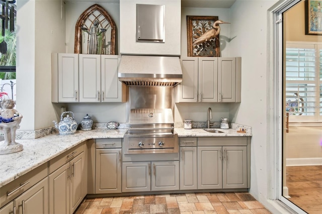 kitchen with sink, wall chimney range hood, and light stone counters