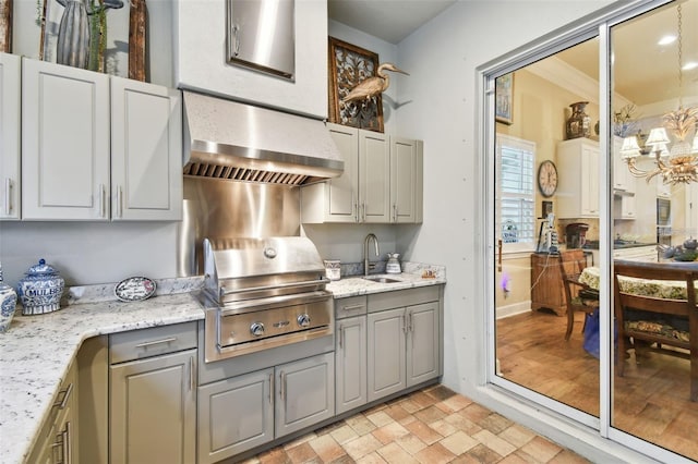 kitchen with gray cabinets, extractor fan, sink, and a notable chandelier