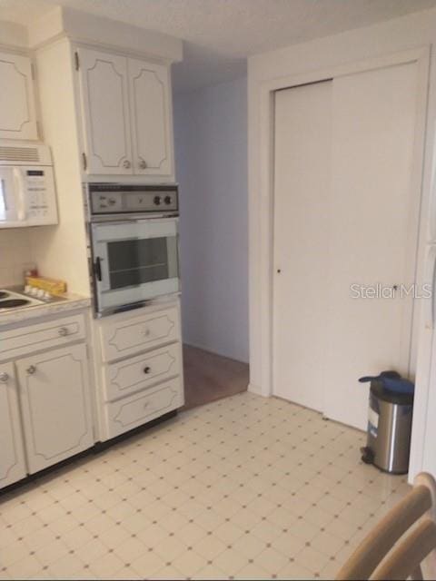 kitchen with white cabinetry and white appliances