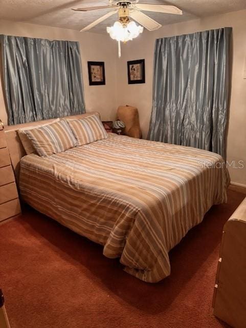 bedroom with ceiling fan, a textured ceiling, and dark colored carpet