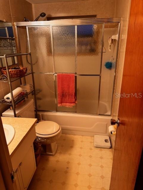 full bathroom with vanity, toilet, and combined bath / shower with glass door