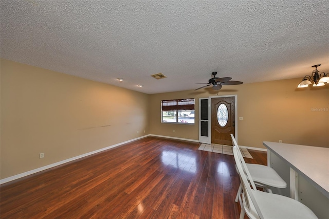 entrance foyer with ceiling fan with notable chandelier, a textured ceiling, and dark hardwood / wood-style flooring