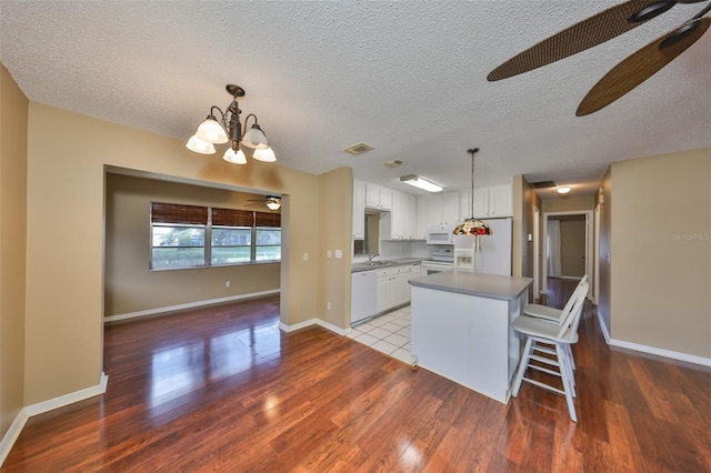 kitchen with white cabinetry, white appliances, a kitchen island, and pendant lighting