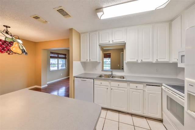 kitchen with light tile patterned flooring, white cabinetry, sink, white appliances, and a textured ceiling